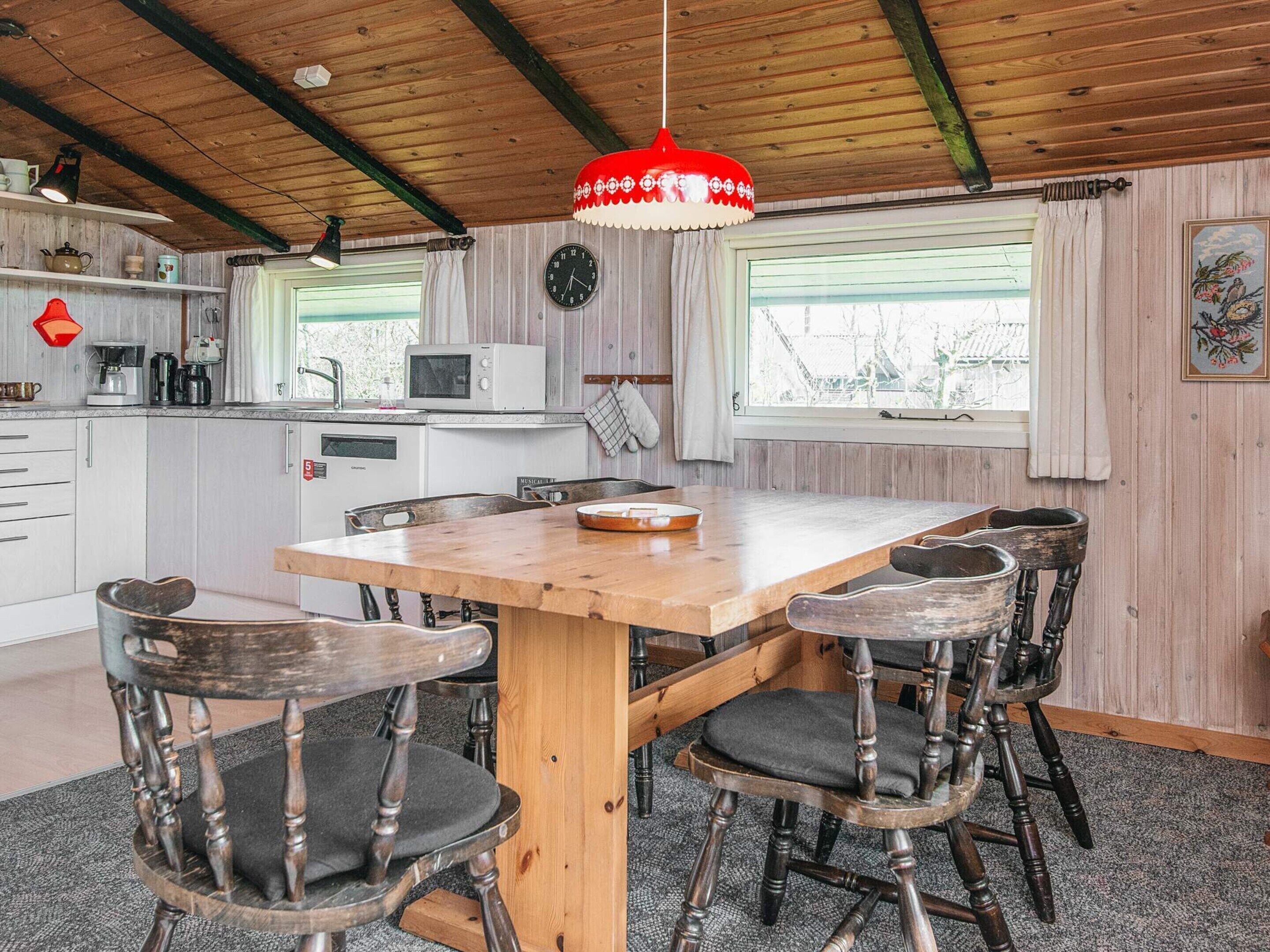 Eine rustikale Küche mit Holzschränken, einem Holztisch und alten Stühlen.