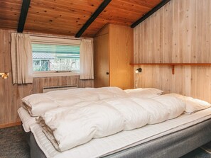 A wooden cabin bedroom with a bed, a window with curtains, a wall-mounted light, and a wooden ceiling. - Superb Holiday Home in Hemmet near Sea (Hemmet)