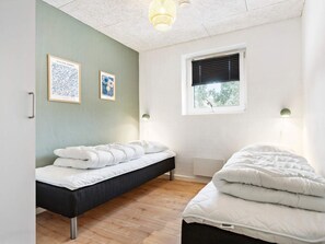 A room with a bed, a bedside table, a window with blinds, and two framed pictures on the wall. - 5 Star Holiday Home in Glesborg (Glesborg)