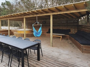 An outdoor patio with a wooden table and chairs, a hanging hammock, and a built-in sofa under a wooden pergola. - 5 Star Holiday Home in Glesborg (Glesborg)