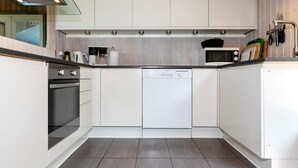 Una cocina moderna con armarios blancos, lavavajillas y estufa.