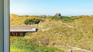 Paisaje costero con casas tradicionales entre dunas, visto desde una ventana.