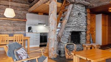 Un interior rústico con chimenea de piedra, muebles de madera y una cocina al fondo.