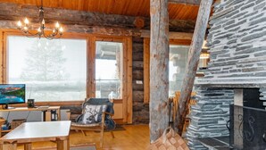 Un intérieur chaleureux de chalet en bois, avec une cheminée en pierre, des meubles en bois et de grandes fenêtres.