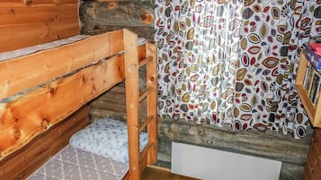 A wooden bunk bed with a patterned curtain and a small shelf with books.