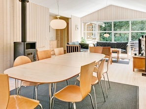 A modern interior with a large oval table, wooden chairs, a television, and a view of greenery through large windows. - 5 Star Holiday Home in Aakirkeby (Akirkeby)