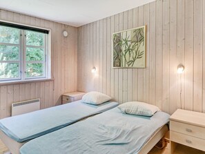 Ein Zimmer mit zwei Betten, einem Fenster, einer Heizung und einer Wandleuchte.