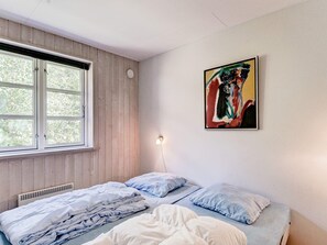 Un dormitorio con cama, ventana y un cuadro en la pared.