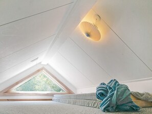 A room with a sloped ceiling, a skylight, a bed with a blue blanket, and a wall-mounted light fixture. - 5 Star Holiday Home in Aakirkeby (Akirkeby)
