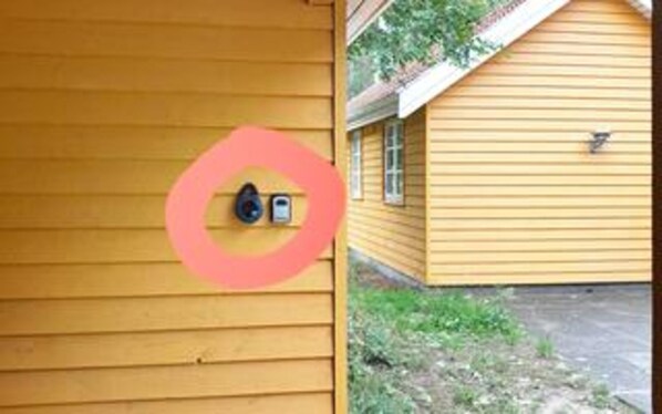 A yellow building with a door featuring a circular lock and a small window. - 5 Star Holiday Home in Aakirkeby (Akirkeby)