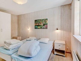 Un dormitorio con una cama, mesitas de noche, un cuadro y un radiador.