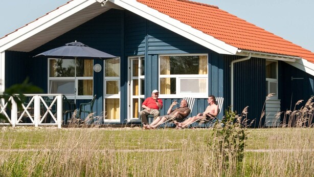 A house with a red roof, a satellite dish, and a porch with chairs.