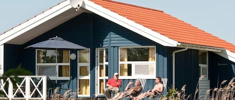 A house with a red roof, a satellite dish, and a porch with chairs.