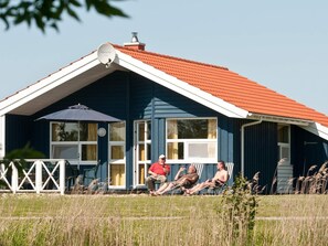 A house with a red roof, a satellite dish, and a porch with chairs. - Holiday Home in Otterndorf (Otterndorf)