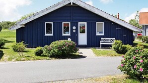 Une maison de plain-pied avec un toit à pignon, une porte d’entrée et deux fenêtres.