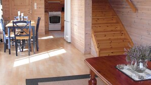 Een houten interieur met een eethoek, keuken en een trap.