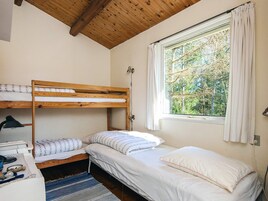 Et værelse med køjesenge, et skrivebord og et vindue med gardiner.