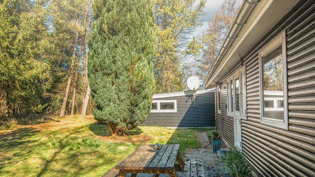 A wooden picnic table in a backyard with a house and a large tree. - 5 Person Holiday Home in Hojslev (Hojslev)