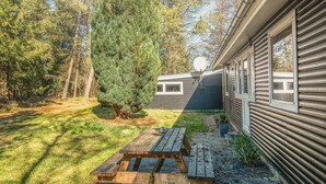A wooden picnic table in a backyard with a house and a large tree. - 5 Person Holiday Home in Hojslev (Hojslev)
