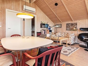A cozy room with a dining table, chairs, a sofa, and a bookshelf.