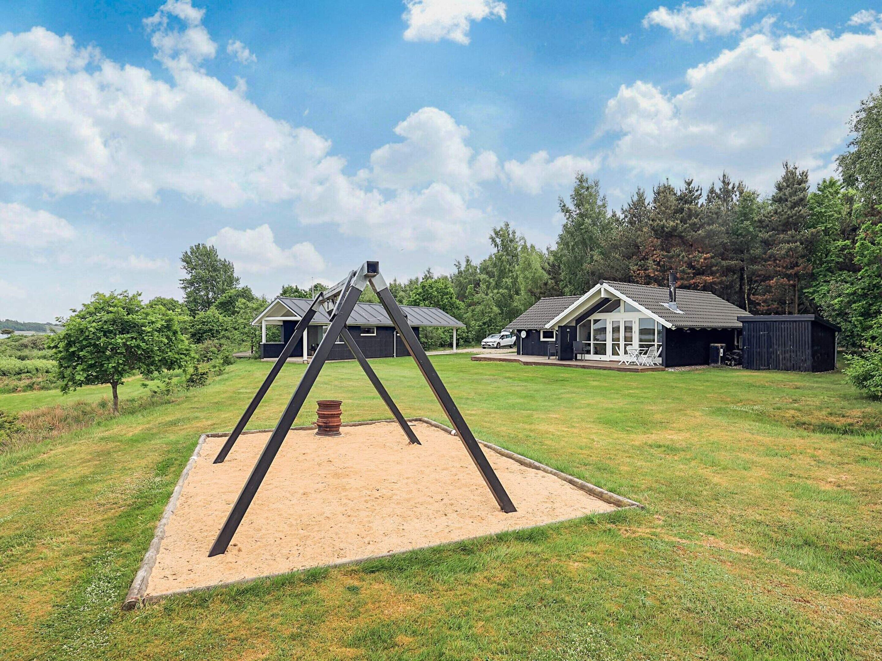 A swing set in a grassy area with a house and a shed in the background.