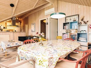 A dining area with a table covered in a floral tablecloth, surrounded by chairs.