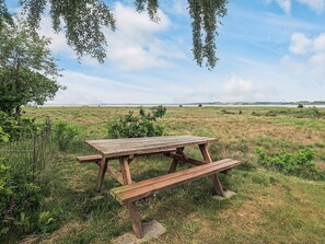 A picnic table in a grassy field with a view of distant hills. - 5 Star Holiday Home in Hojslev (Hojslev)