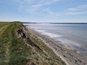A coastal landscape with a grassy path leading to a sandy beach. - 5 Star Holiday Home in Hojslev (Hojslev)