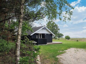 A black building with a white roof, surrounded by greenery and a clear sky. - 5 Star Holiday Home in Hojslev (Hojslev)
