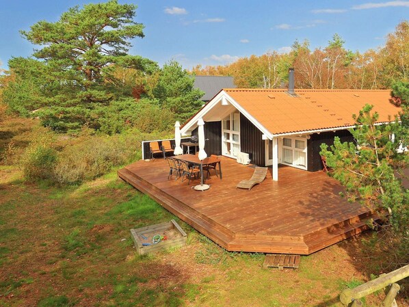 A cabin with a wooden deck, a dining area, and a large window. - 8 Person Holiday Home in Laeso (Læsø)