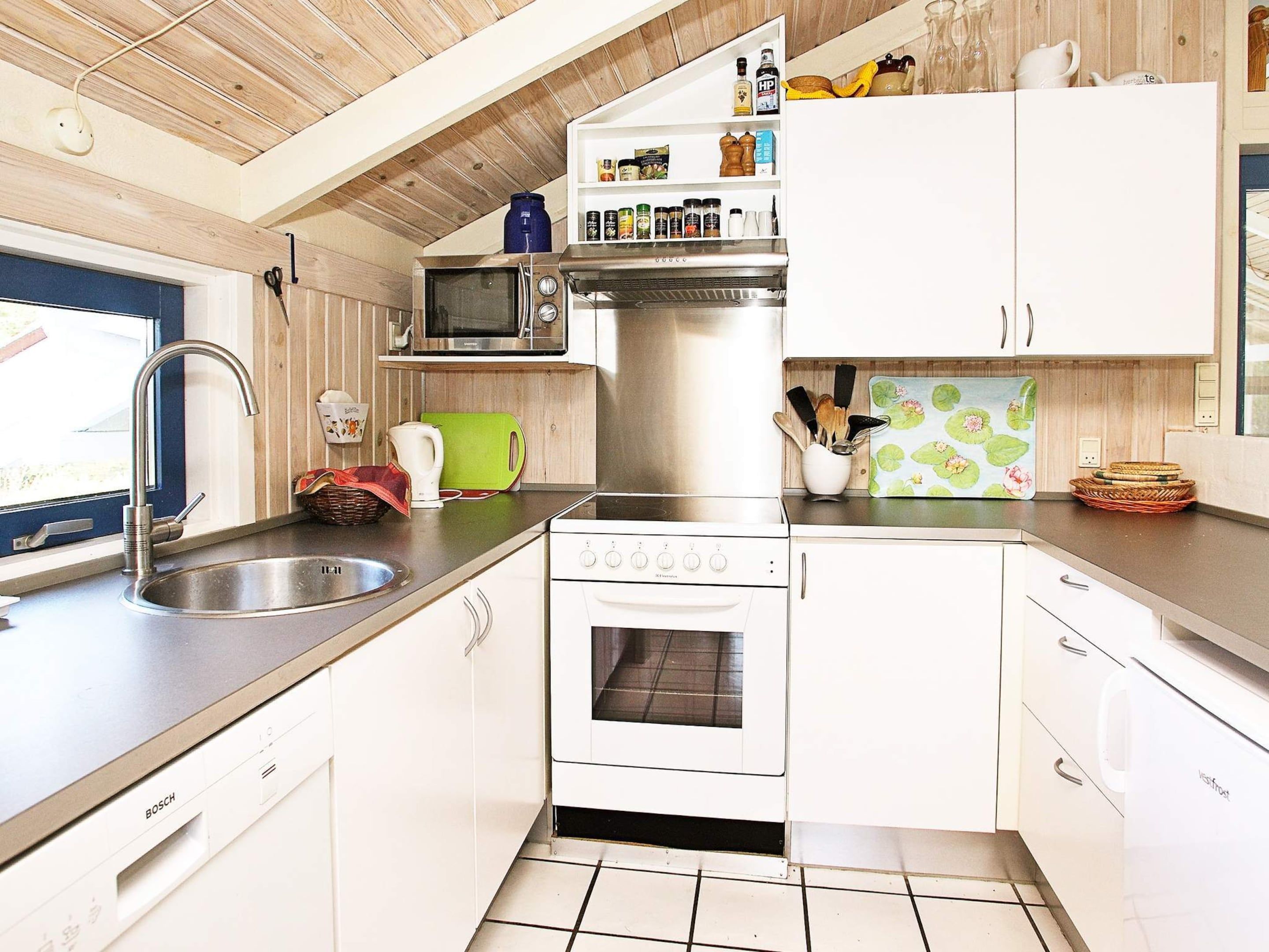 A compact kitchen with a Bosch dishwasher, a microwave, and a stove.