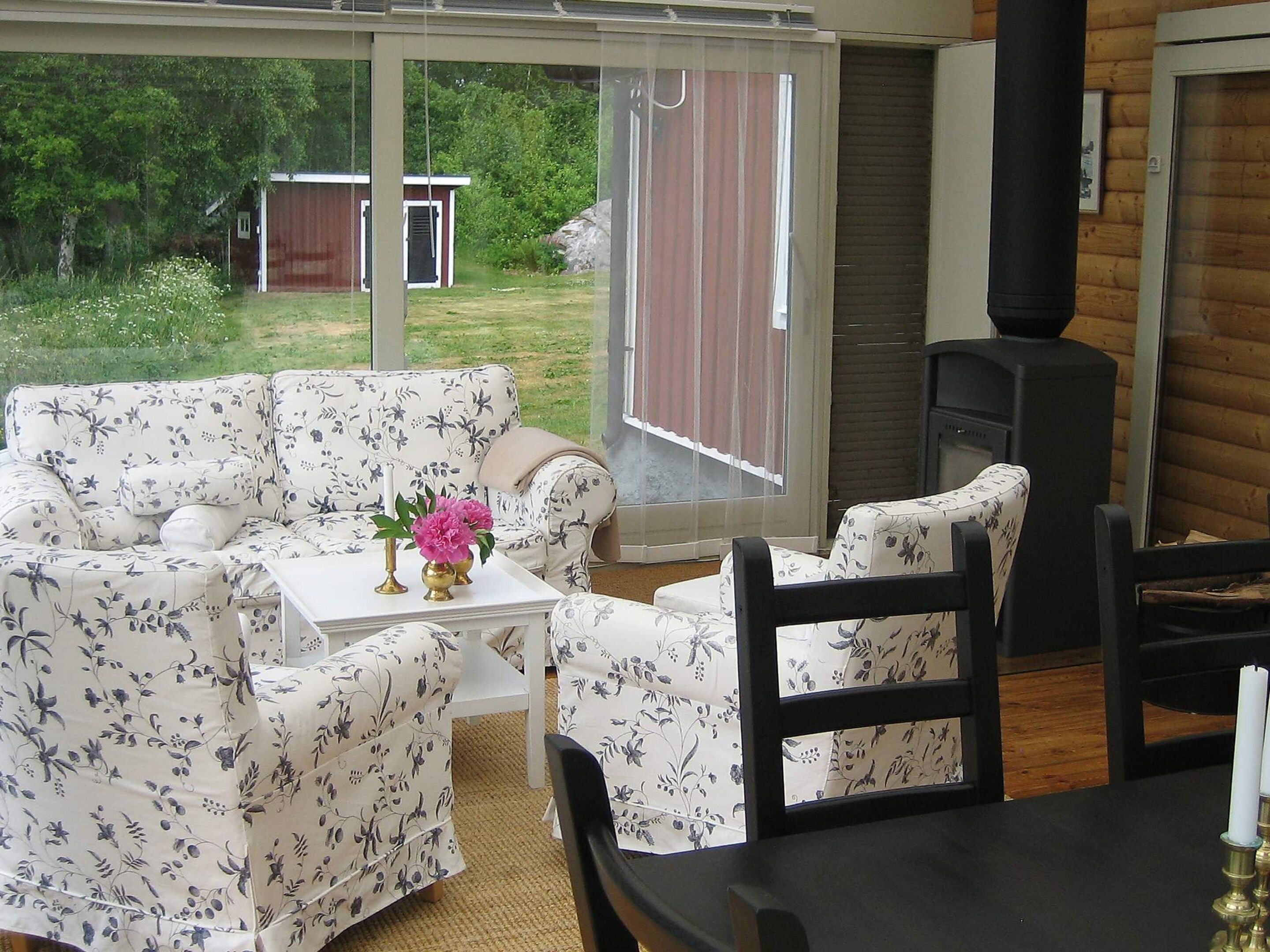 A room with a sofa, a table with a vase, and a chair.