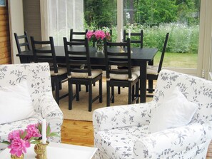 A dining area with a table and chairs, a window with a view of greenery, and floral-patterned sofas. - Holiday Home in Åtvidaberg (Atvidaberg)