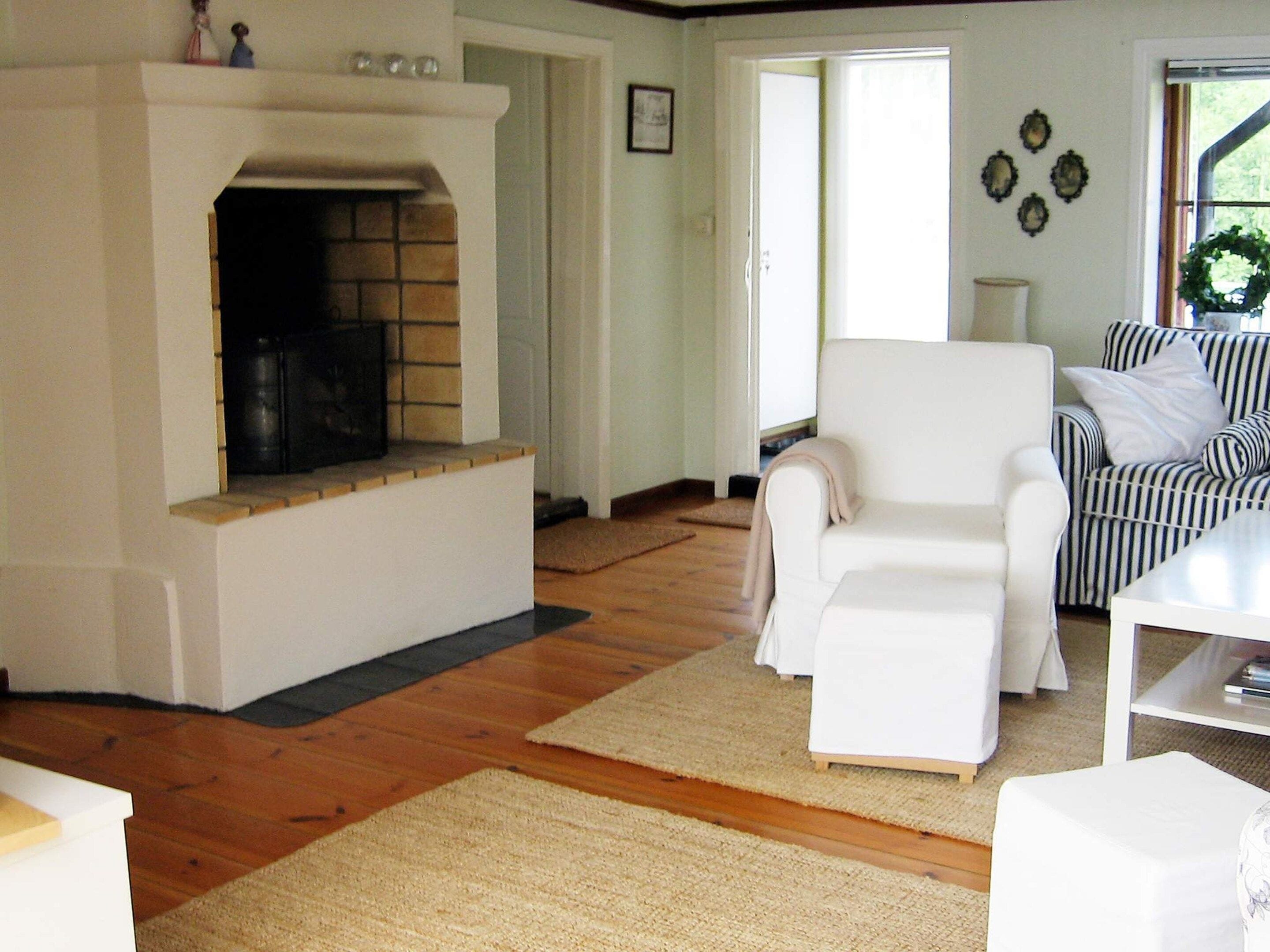 A living room with a fireplace, a white armchair, and a striped sofa.