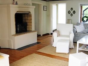 A living room with a fireplace, a white armchair, and a striped sofa. - Holiday Home in Åtvidaberg (Atvidaberg)