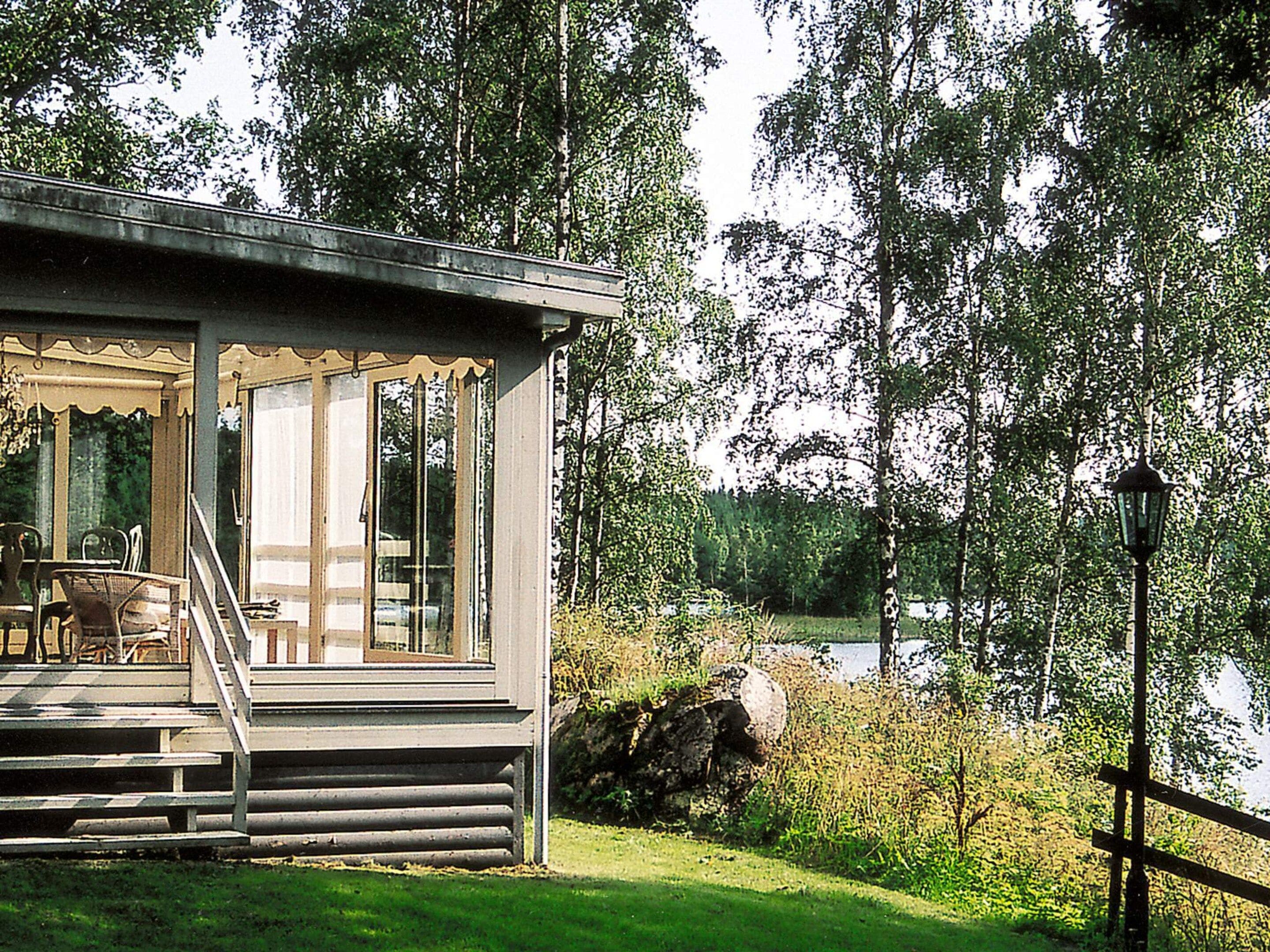 Een vakantiehuis met een veranda, uitzicht op een meer en een bebost gebied.
