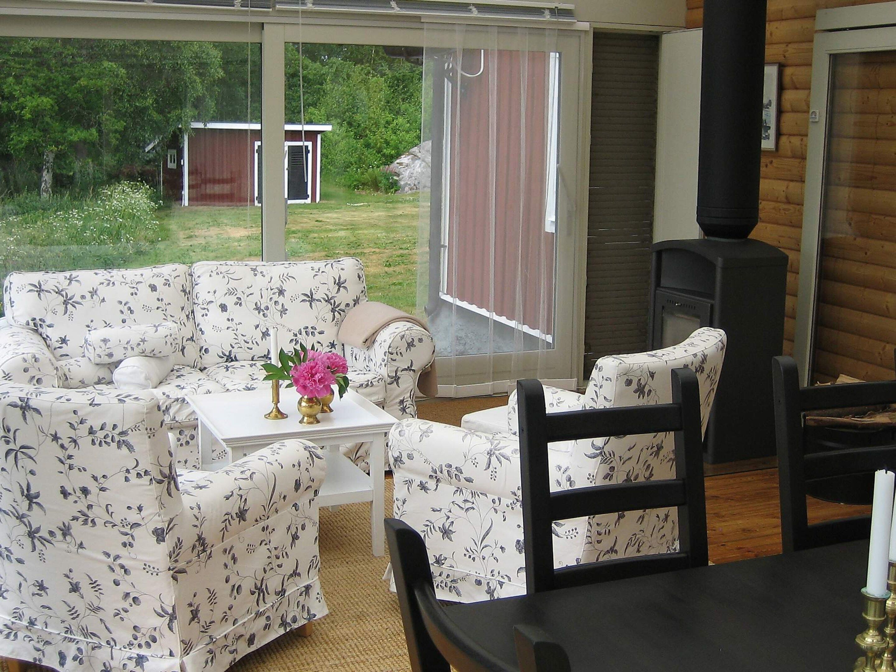 Een gezellig patio met een bloemenbank, een kleine tafel met een vaas en een zwarte stoel.