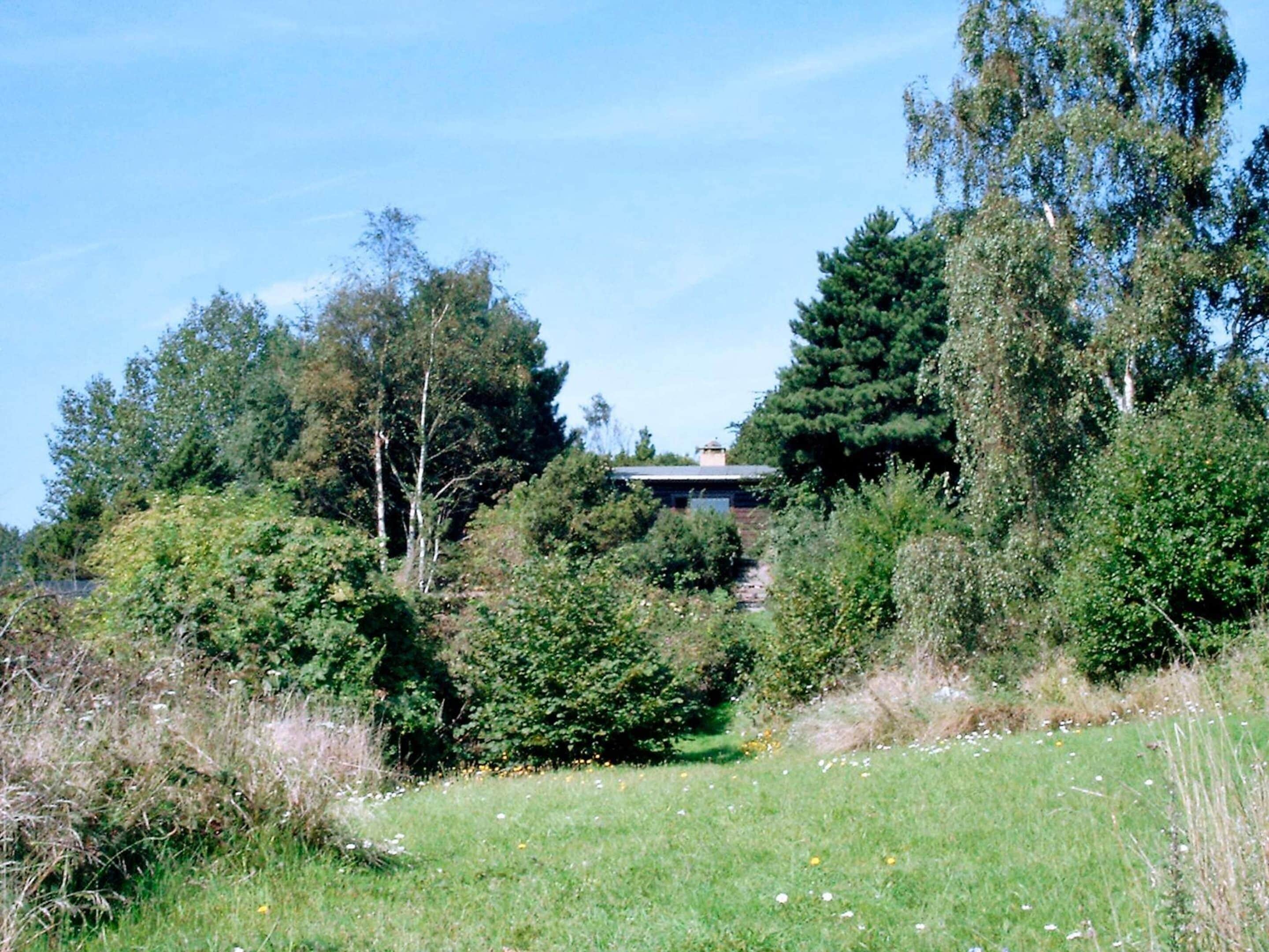 A natural landscape with dense trees and a building partially obscured by foliage.