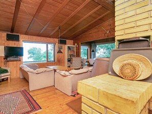 A cozy cabin interior with wooden walls, a fireplace, a television, and a bookshelf. - 6 Person Holiday Home in Rudkobing (Rudkobing)