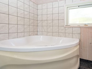 A bathroom with a bathtub, tiled walls, and a window.
