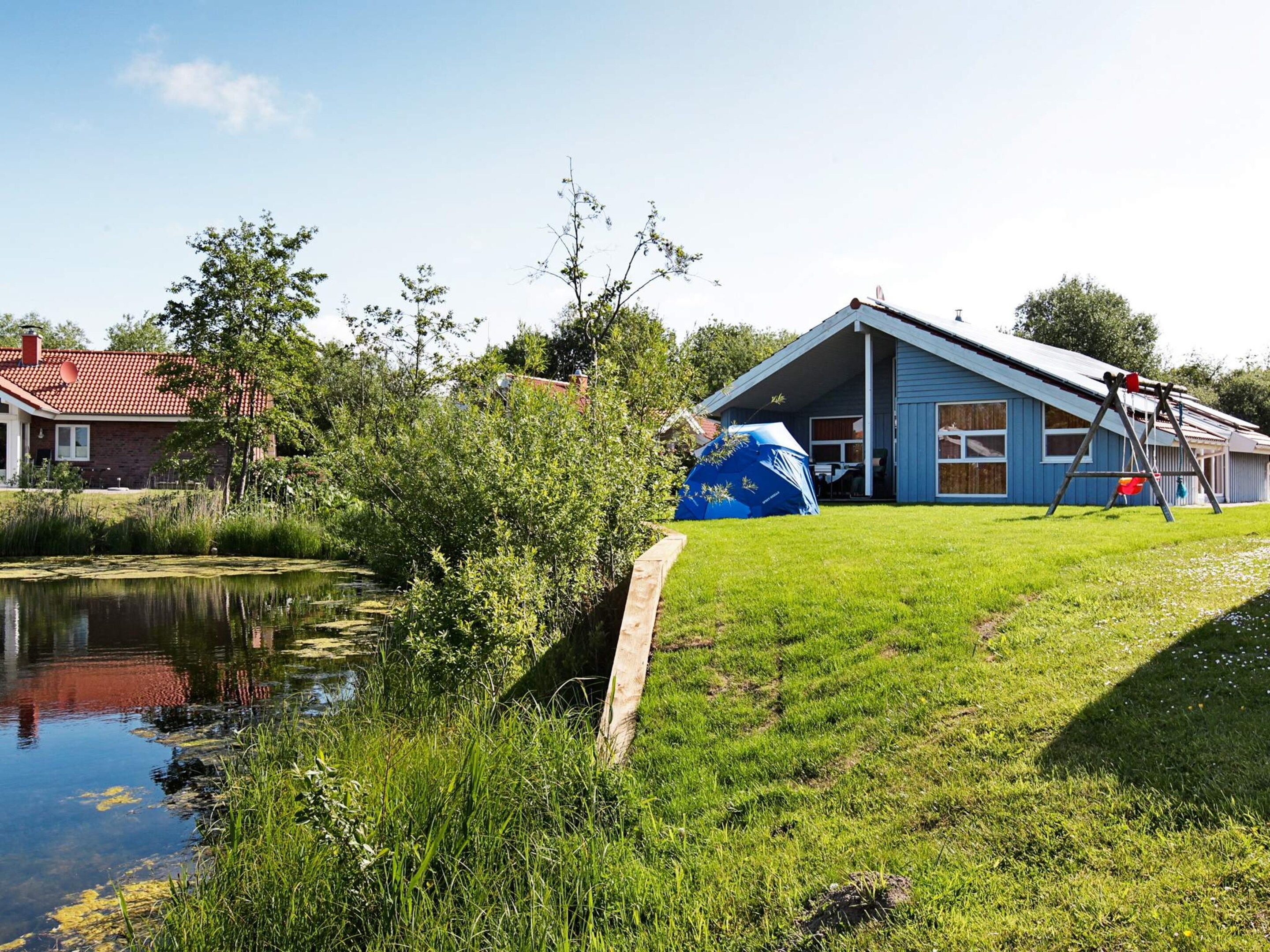 A residential area with a house, a pond, and a swing set.