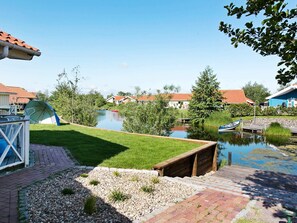 A riverside view with a grassy area, a wooden dock, and a small boat.