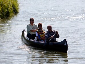 A group of people in a canoe on a calm body of water.