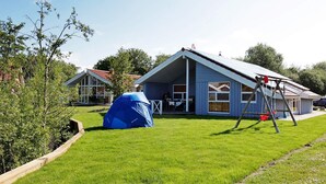 Una propiedad residencial con un césped amplio, una carpa azul y un columpio.