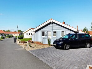 A residential building with a blue exterior, a paved driveway, and a parked car.
