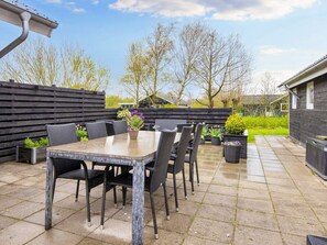 An outdoor patio with a table and chairs, surrounded by a wooden fence and potted plants. - 4 Star Holiday Home in Hemmet (Hemmet)