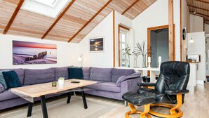 A modern living room with a wooden ceiling, a purple sofa, a wooden coffee table, and a black leather chair.