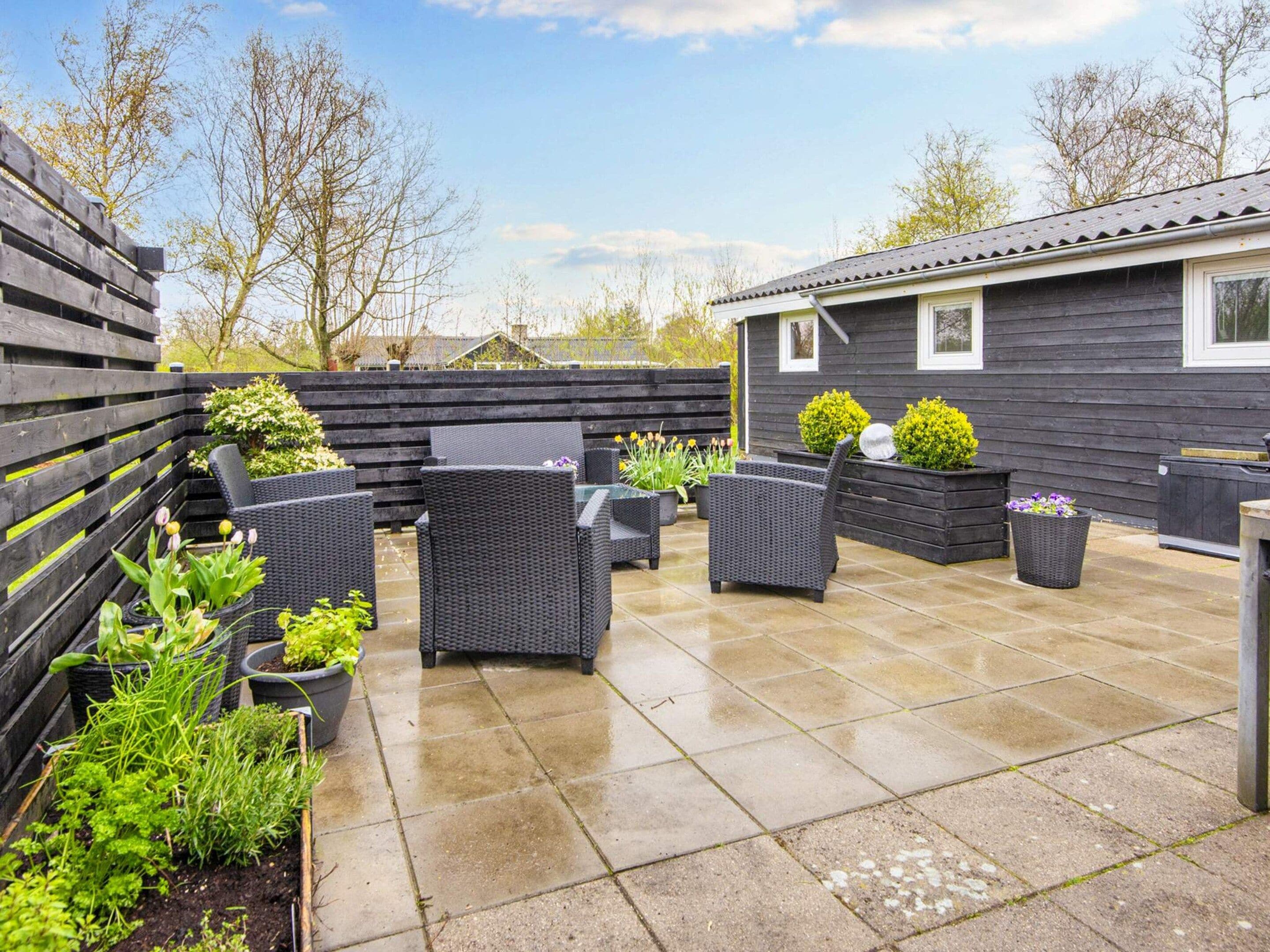 A patio area with outdoor furniture, potted plants, and a building in the background.
