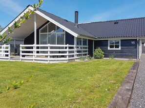 A two-story building with a sloped roof, a fenced outdoor seating area, and a well-maintained lawn.