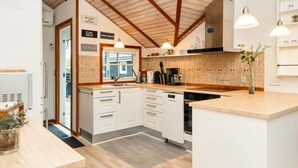 A modern kitchen with white cabinets, a wooden countertop, and a tiled backsplash.
